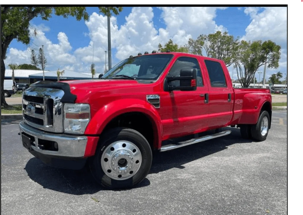 Red pickup truck parked under blue sky.